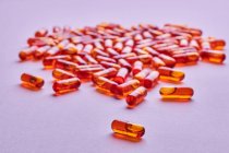 Состав оранжевых таблеток, разбросанных на розовом фоне в светлой студии — стоковое фото