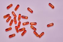 Top vista composição de pílulas laranja espalhadas no fundo rosa em estúdio de luz — Fotografia de Stock