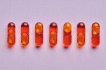 Vista dall'alto composizione di pillole arancioni su sfondo rosa in studio di luce — Foto stock