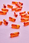 Composizione di pillole arancioni sparsi su sfondo rosa in studio luce — Foto stock