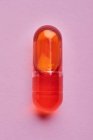 Состав оранжевых таблеток на розовом фоне в светлой студии — стоковое фото