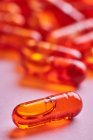 Composición de pastillas de color naranja dispersas sobre fondo rosa en estudio de luz - foto de stock
