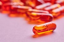 Composición de pastillas de color naranja dispersas sobre fondo rosa en estudio de luz - foto de stock