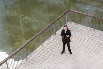 Свыше среднего возраста бородатый мужчина в элегантном костюме просматривает планшет на террасе — стоковое фото