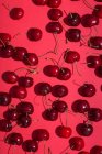From above bright red appetizing cherries with stems on pink background — Stock Photo