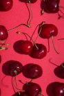 Сверху ярко-красные аппетитные вишни со стеблями на розовом фоне — стоковое фото