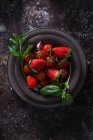 Vista superior da tigela com morango fresco e tomates para preparar uma sopa fria de gaspacho colocada na mesa escura — Fotografia de Stock