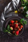 Vista dall'alto della ciotola con fragola fresca e pomodori per preparare un gazpacho zuppa fredda posta sul tavolo scuro — Foto stock