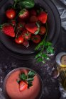 Vue du dessus des bols à la fraise fraîche gaspacho soupe froide placée sur la table noire — Photo de stock