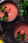 Draufsicht auf Schüsseln mit frischer Erdbeer Gazpacho-Suppe auf dunklem Tisch — Stockfoto