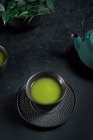 Taza de cerámica negra con té matcha tradicional japonés de color verde servido en la mesa con tetera - foto de stock