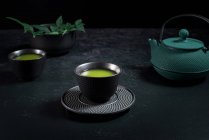 Tazza di ceramica nera con tradizionale tè matcha verde giapponese servito sul tavolo con teiera — Foto stock