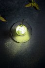 Hoher Glaswinkel mit kaltem grünen Matcha Latte mit Milch serviert mit Stroh auf Untertasse auf schwarzem Tisch — Stockfoto