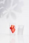 Здоровый освежающий детоксикации воды с свежей спелых нарезанных клубники подается в прозрачном стекле против белой стены с тенями — стоковое фото