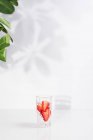 Desintoxicação refrescante saudável infundiu água com morangos maduros fatiados servidos em vidro transparente contra a parede branca com sombras — Fotografia de Stock