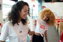 Entzückte junge afroamerikanische Freundinnen trinken Kaffee im Café und genießen das Wochenende zusammen — Stockfoto