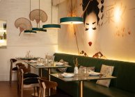 Gemütliches Interieur eines asiatischen Restaurants mit bequemen Sofas und Glastischen serviert mit Geschirr — Stockfoto
