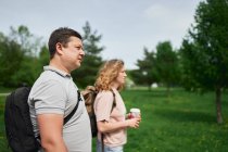 Vista laterale della coppia che si gode una passeggiata insieme nel lussureggiante parco durante la giornata estiva — Foto stock