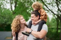 Delighted loving couple with adorable child spending time together in summer park and enjoying weekend — Stock Photo