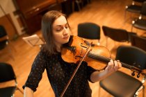 Dall'alto musicista professionista focalizzata suonare violino acustico con gli occhi chiusi con spartito musicale durante le prove in studio — Foto stock