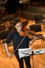 Do acima mencionado profissional músico feminino tocando violino acústico e olhando para a folha de música durante o ensaio em estúdio — Fotografia de Stock