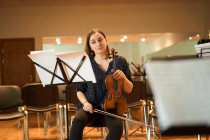 Профессиональная женщина-музыкант играет на акустической скрипке и смотрит на ноты во время репетиции в студии — стоковое фото