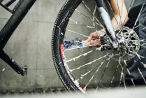 Unrecognizable crop male mechanic cleaning gear cassette of bicycle wheel with brush in workshop — Stock Photo