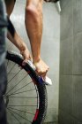 Irriconoscibile coltura maschio meccanico pulizia ingranaggio cassetta della ruota della bicicletta con spazzola in officina — Foto stock