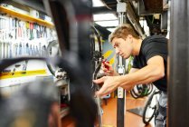 Side view of concentrated male master pumping tyre of bike wheel using inflating gun in workshop — Stock Photo