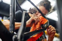 Сосредоточенный мастер вытирания рамы велосипеда тряпкой во время работы в современной мастерской — стоковое фото