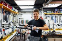 Konzentrierter männlicher Meister wischt Fahrradrahmen mit Lappen ab, während er in der modernen Reparaturwerkstatt vor der Kamera arbeitet — Stockfoto