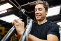 Low angle of man screwing in part of bicycle while working in professional repair workshop — Stock Photo