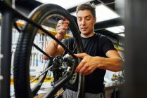 Maschio tecnico fissaggio ruota alla bicicletta mentre si lavora in officina professionale moderna — Foto stock