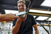 Klient mit niedrigem Anbauwinkel bezahlt mit Smartphone an männlichen Techniker in Reparaturwerkstatt — Stockfoto