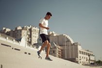 Вид збоку атлетичного чоловіка, що бігає вниз під час тренувань у сонячний день у місті влітку — стокове фото