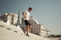 Vista lateral del atlético macho corriendo abajo mientras entrenaba en un día soleado en la ciudad en verano - foto de stock