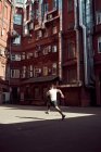 Side view of unrecognizable male runner jumping on street while training in city in summer — Stock Photo