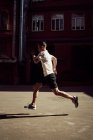 Вид сбоку мужчины, бегающего по улице во время тренировки в городе летом — стоковое фото
