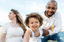 Happy multiethnic family with cute little daughter enjoying summer picnic in nature — Stock Photo