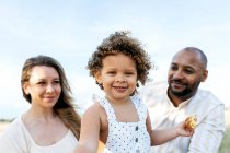 Família multiétnica feliz com filhinha fofa curtindo piquenique de verão na natureza — Fotografia de Stock