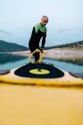 Surfista masculino em roupa de mergulho bombeando prancha SUP enquanto está em pé na praia e se preparando para o surf — Fotografia de Stock