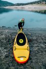 From above male surfer in wetsuit pumping SUP board while standing on seashore and preparing for surfing — Stock Photo
