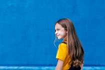 Seitenansicht eines entzückten verträumten Teenagers, der auf blauem Hintergrund wegschaut — Stockfoto
