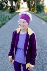 Frohe Seniorin joggt lächelnd auf Asphaltstraße beim Fitnesstraining im Sommer morgens auf dem Land — Stockfoto