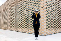 Feminino de jaqueta e gola alta usando óculos VR perto de janelas de construção à luz do dia — Fotografia de Stock