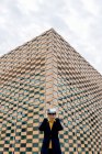 Mujer con chaqueta y cuello alto usando gafas VR cerca de las ventanas del edificio a la luz del día - foto de stock