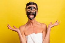 Fröhliche Frau mittleren Alters mit schwarzer abgeblätterter Maske steht auf gelbem Studiohintergrund und schaut in die Kamera — Stockfoto