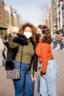 Due amici scattano un autoritratto in strada in una giornata di sole indossando maschere — Foto stock