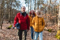 Lächelndes Paar und Teenager-Tochter spazieren mit Plaid im Wald zum Picknick im Herbst — Stockfoto