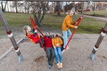De cima de família encantada equitação balanço líquido no playground no parque de outono e se divertindo juntos — Fotografia de Stock
